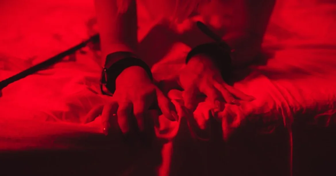 Navigating Your First BDSM Experience: A Step-by-Step Educational Guide A woman grabbing the sheets with her nails in ecstasy as she has her first BDSM experience.