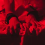 A woman grabbing the sheets with her nails in ecstasy as she has her first BDSM experience.