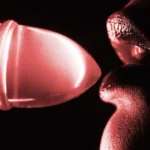 An image of a sex positive woman putting a sex toy to her lips seductively, representing sex positivity.