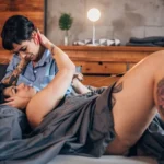 A couple intimately in an embrace during BDSM aftercare. They are focused on emotionally debriefing for well-being.