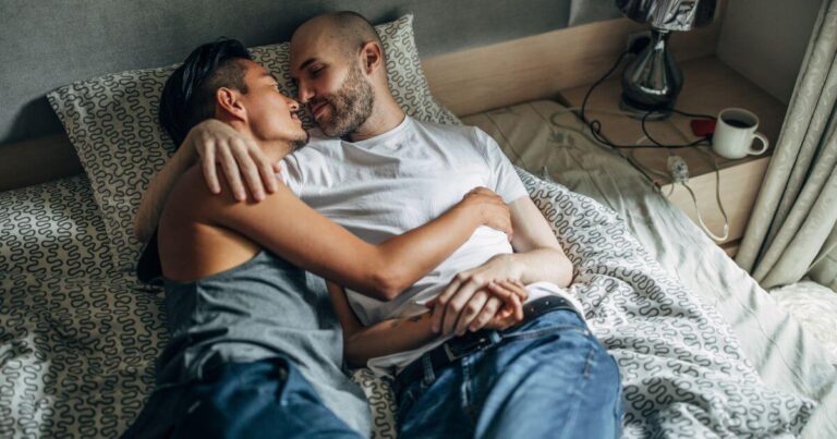 A couple intimately cuddling in bed, demonstrating what is aftercare.