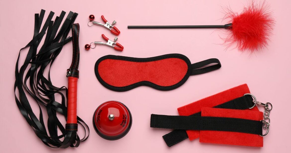 BDSM Classes: Your Ultimate Guide to Starting Your BDSM Journey BDSM classes background of toys on a pink sheet.