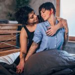 Lesbian couple cuddling in bed, illustrating neurodivergent BDSM aftercare with comforting physical closeness.