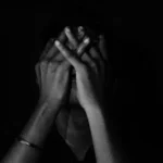 A person sitting in the darkness depressed and dealing with drop in BDSM.