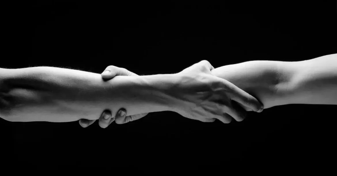 Rebuilding Trust After a Scene Goes Wrong: Healing Steps for BDSM Relationships Two hands holding each other at the forearm in a dark room rebuilding trust in BDSM.