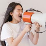A woman speaking with her dominant voice into a megaphone.