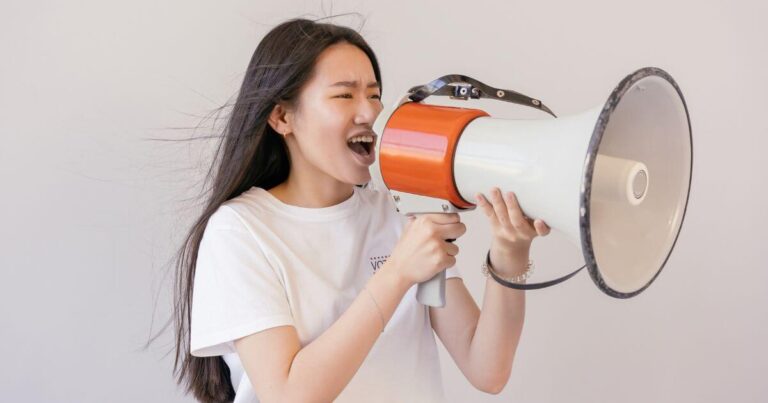 A woman speaking with her dominant voice into a megaphone.